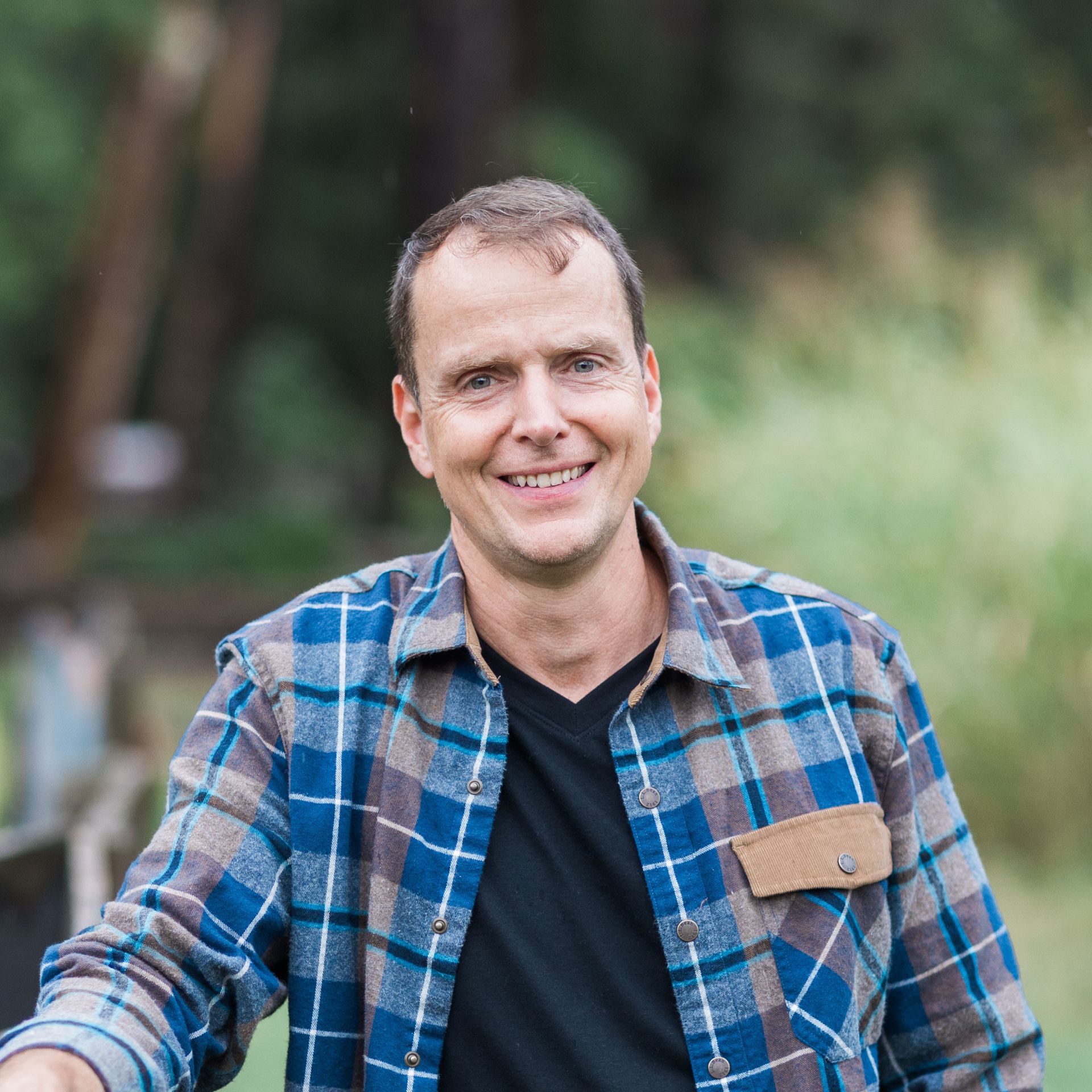 Aaron Hartman MD leaning against a fence on his property
